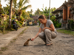 Woman Saved More Than 2000 Dogs After Finding One Tiny Puppy Woman kneeling beside a tiny rescued puppy on a quiet road in Bali