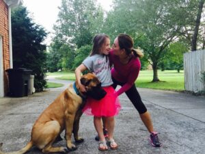 Mother, daughter and mastiff at play
